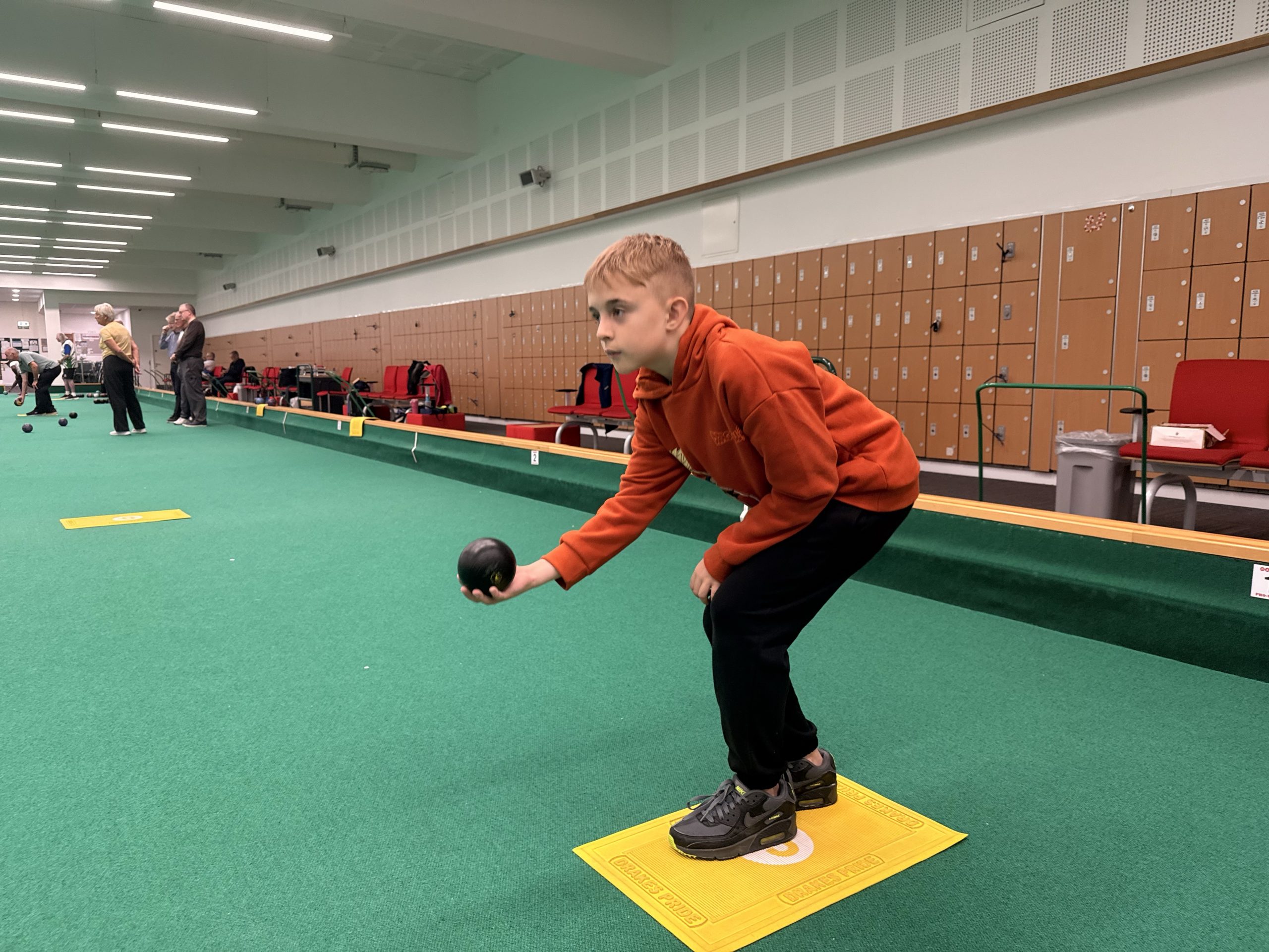 A young child playing bowls